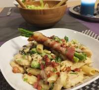 Penne alla carbonara with chicken, pancetta, mushrooms, broccoli, green peas topped with parmesan cheese, bacon bits and asparagus wrapped with bacon. 