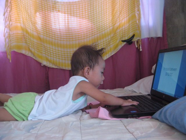 cute lil baby busy watching on the laptop