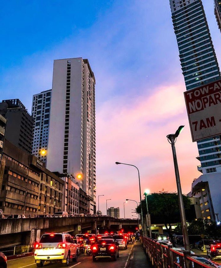 Pinkish sunset complemented by the heavy traffic build up and urbanscape, city life  